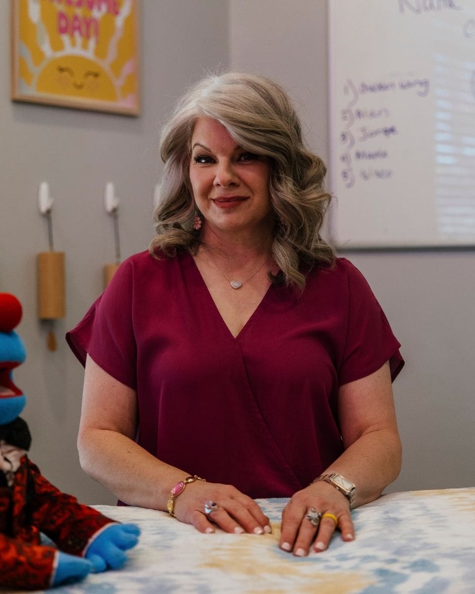 Amy Barilla, Reiki Master Educator, smiling at a table in her Las Vegas practice space