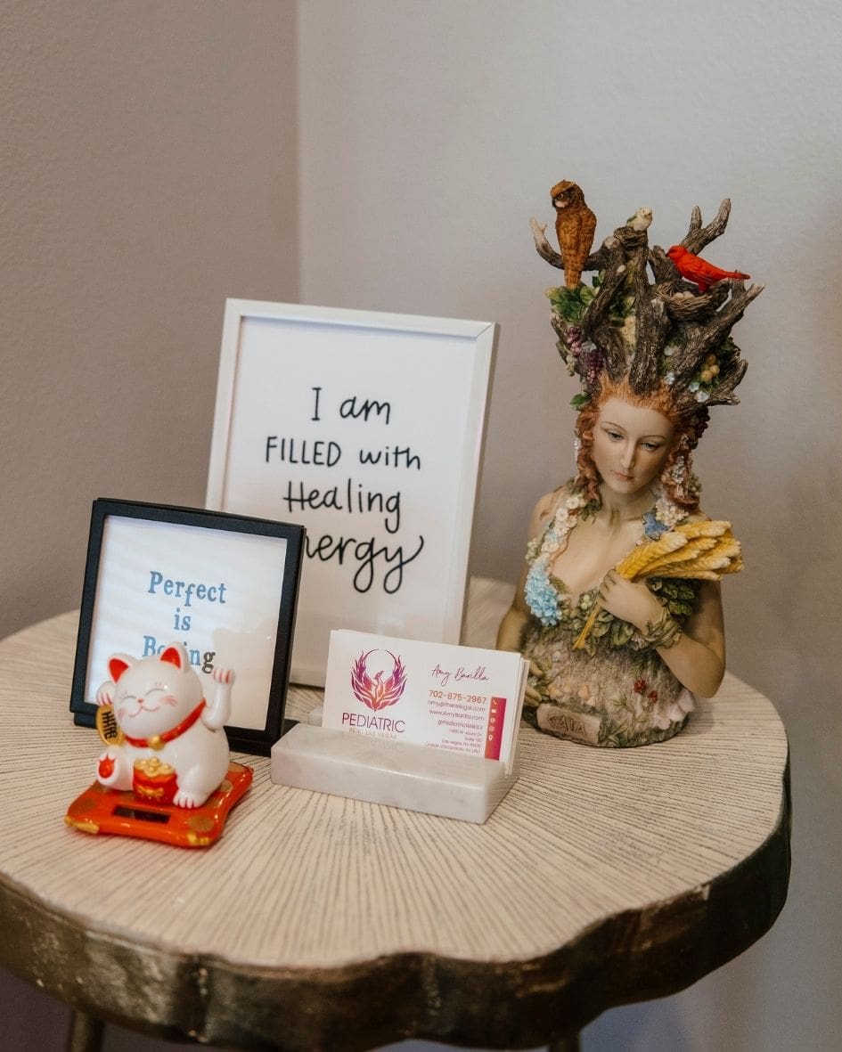 Wood side table with a framed "I am filled with healing energy" sign and Pediatric Reiki LV business cards